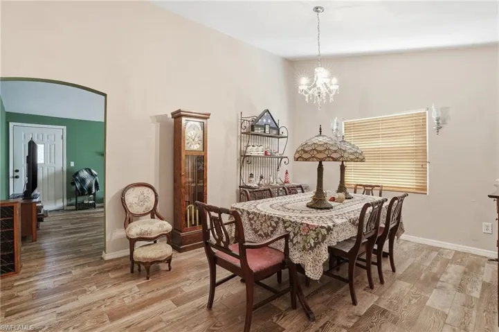 Dining room featuring light wood-style flooring, arched walkways, and suspended lighting