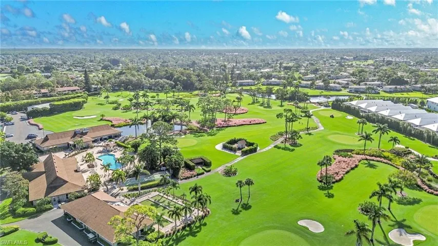 Aerial perspective of suburban area featuring a local golf course and a nearby body of water