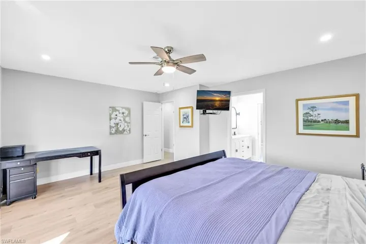 Bedroom with light wood-type flooring, recessed lighting, ceiling fan, and ensuite bathroom