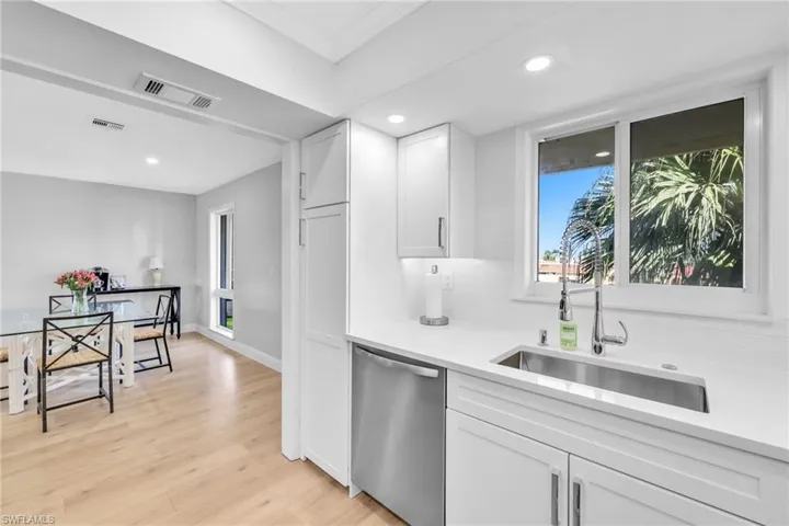 Kitchen featuring stainless steel dishwasher, white cabinetry, light wood-style floors, recessed lighting, and tasteful backsplash