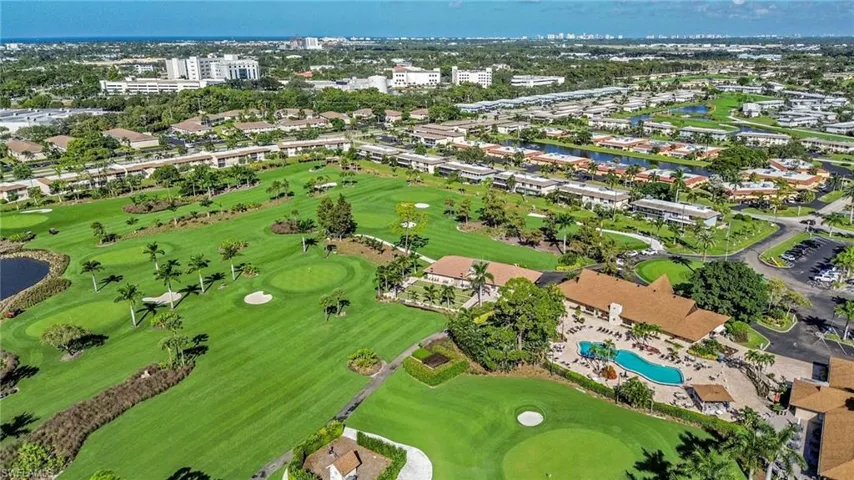 Aerial view of property and surrounding area featuring a nearby body of water and a golf club
