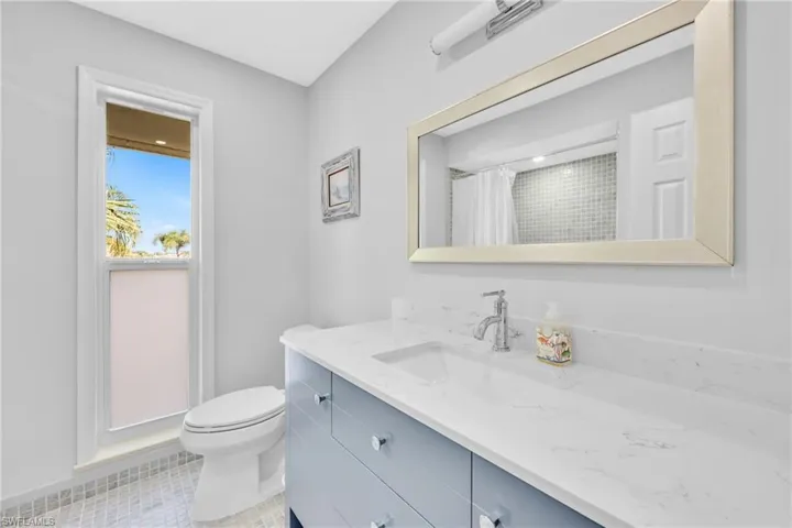 Bathroom featuring vanity, light tile patterned floors, and curtained shower