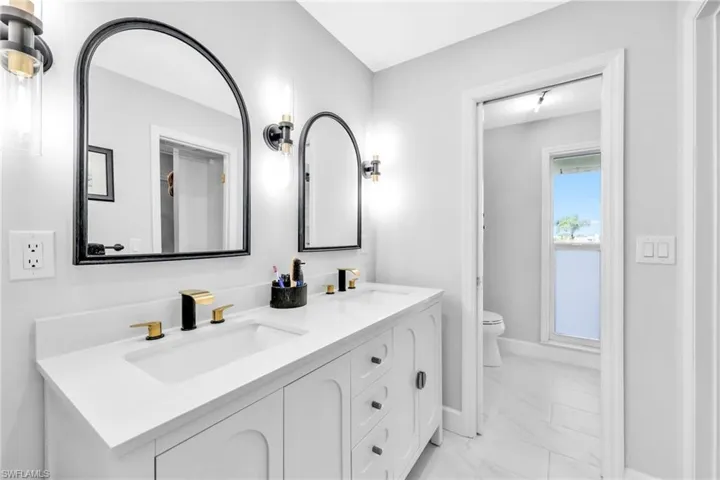 Bathroom with double vanity and light marble finish flooring