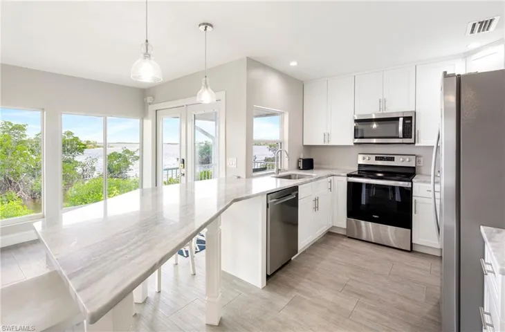 Kitchen with appliances with stainless steel finishes, white cabinets, pendant lighting, plenty of natural light, and recessed lighting