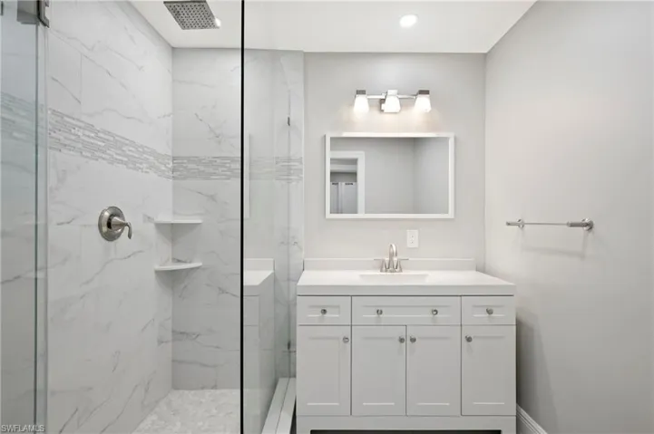 Bathroom featuring a marble finish shower and vanity