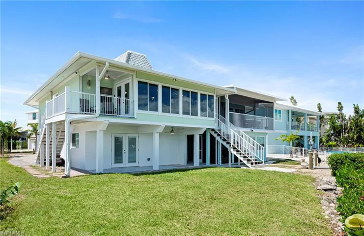 Rear view of property with stairs, a patio area, ceiling fan, a yard, and french doors