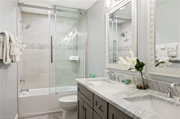 Bathroom with combined bath / shower with glass door and double vanity