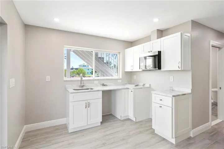 Kitchen featuring white cabinets, stainless steel microwave, light wood-type flooring, and recessed lighting
