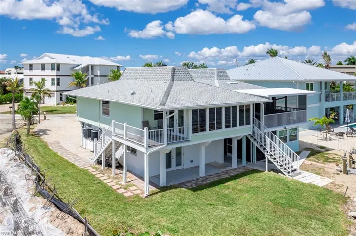 Back of property featuring stairs, a patio, a yard, a deck, and roof with shingles