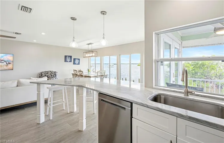 Kitchen featuring white cabinets, stainless steel dishwasher, hanging light fixtures, healthy amount of natural light, and recessed lighting