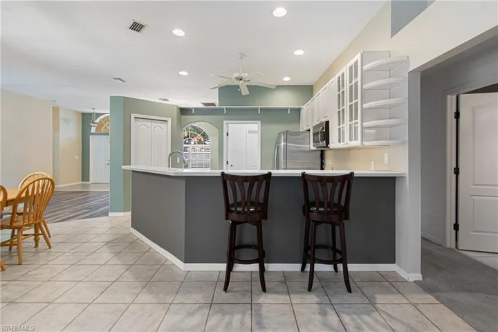 Kitchen with white cabinets, stainless steel appliances, a kitchen breakfast bar, and kitchen peninsula