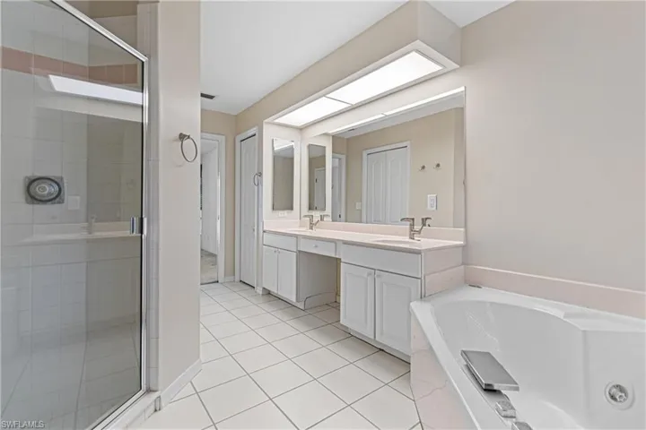 Bathroom featuring plus walk in shower, dual vanity, and tile patterned flooring