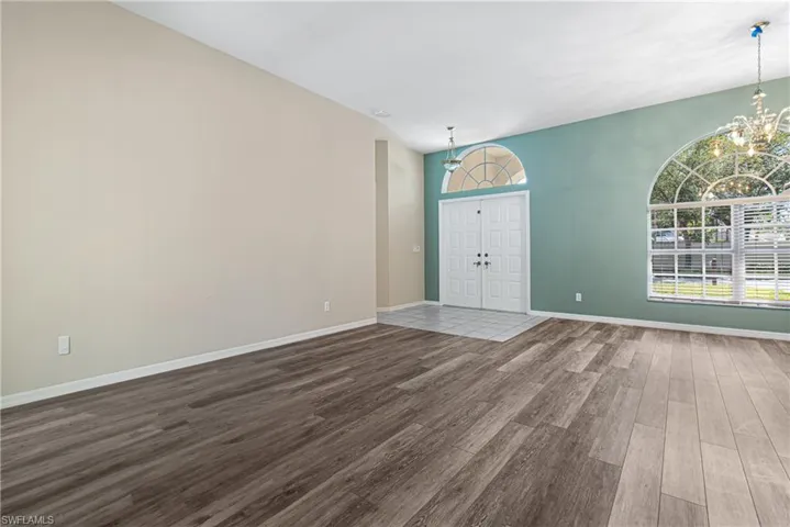 Unfurnished formal living/ dining room with new wood-type flooring and a chandelier