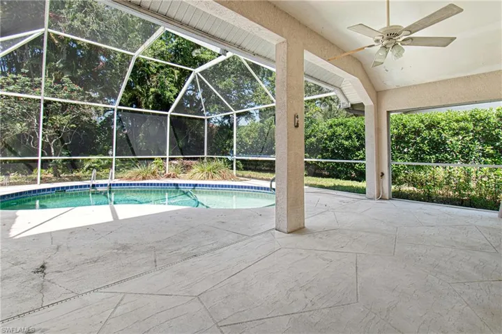 View of pool with screened enclosure, ceiling fan, and a patio area