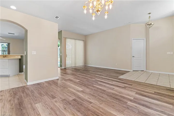 Formal living/ dining room featuring light new hardwood / wood-style floors and a notable chandelier