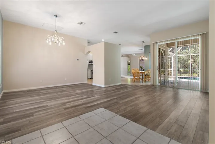formal living/ dining room with light new hardwood / wood-style floors and a notable chandelier