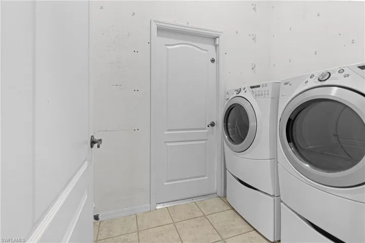 Laundry area with light tile patterned flooring and separate washer and dryer