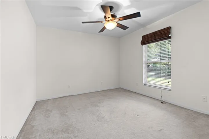 Carpeted spare bedroom featuring ceiling fan and a healthy amount of sunlight