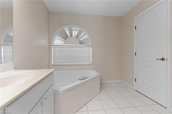 Bathroom with a washtub, tile patterned floors, and vanity