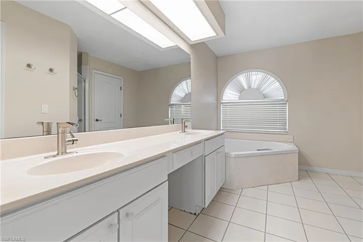 Bathroom featuring a tub to relax in, tile patterned floors, and double vanity