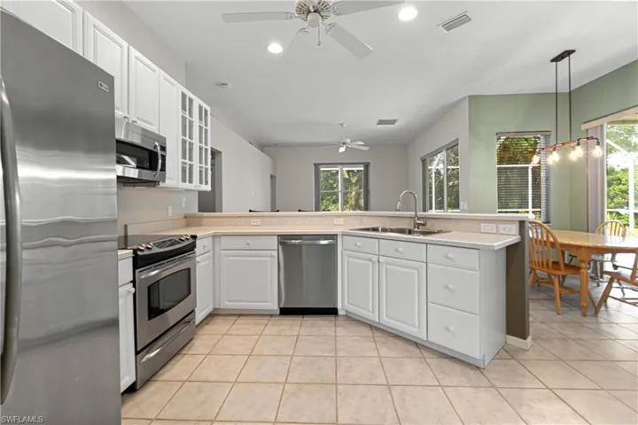 Kitchen featuring stainless steel appliances, sink, pendant lighting, light tile patterned floors, and ceiling fan
