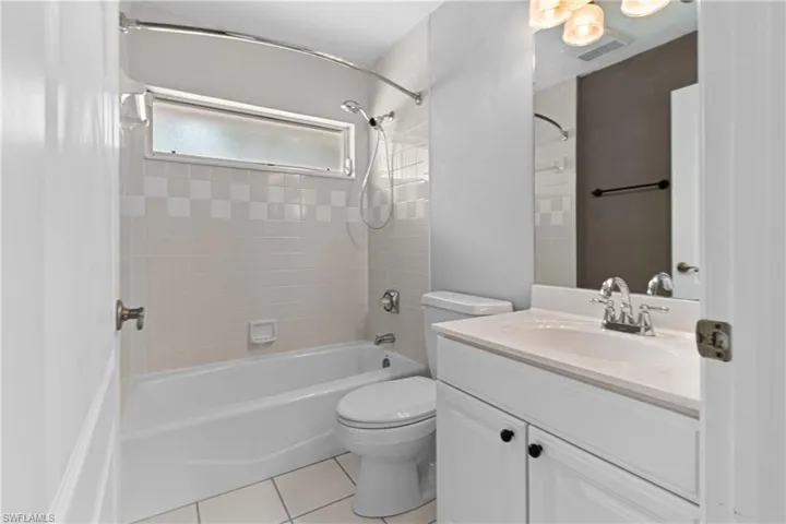 Full bathroom featuring tile patterned flooring, toilet, vanity, and tiled shower / bath