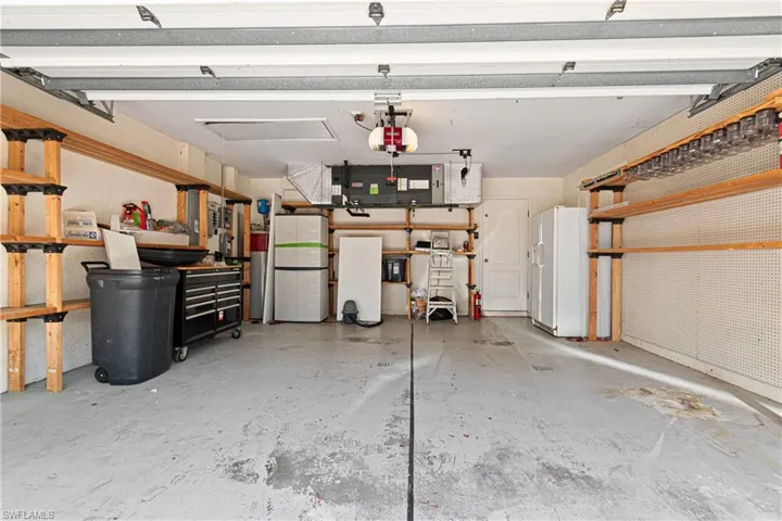 Garage featuring a garage door opener, shelving and white refrigerator