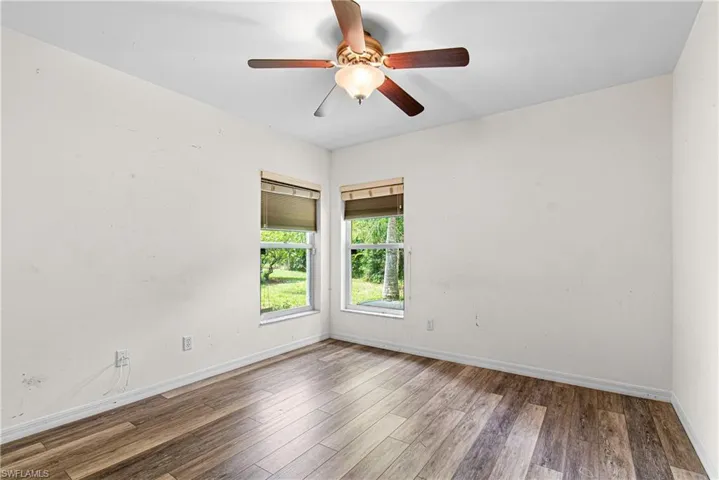 Spare bedroom with ceiling fan and new hardwood / wood-style floors