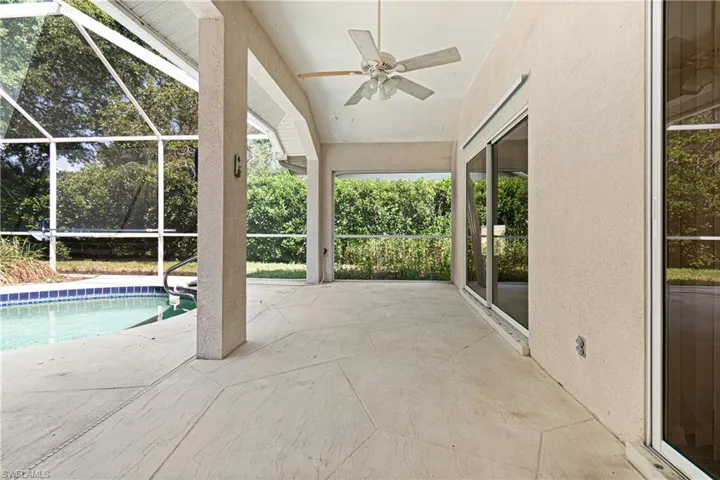 View of pool featuring glass enclosure, a patio area, and ceiling fan