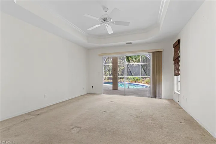 Unfurnished room with ornamental molding, light colored carpet, ceiling fan, and a tray ceiling