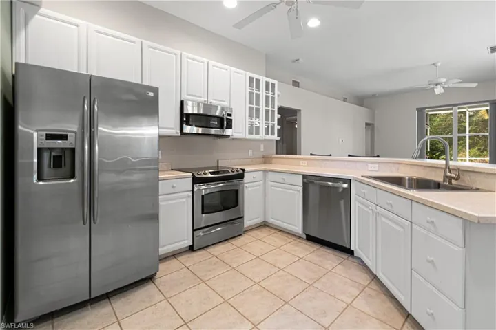 Kitchen with light tile tiles floors, ceiling fan, stainless steel appliances, sink, and kitchen peninsula
