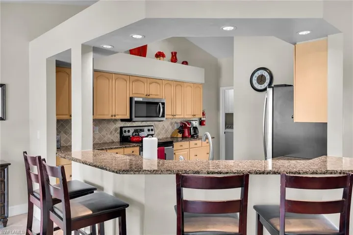 Kitchen featuring granite countertops, wood cabinetry, built-in microwave, and recessed lighting