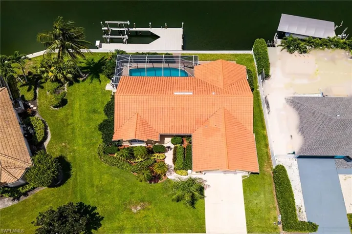 Waterfront property featuring a private boat dock, screened swimming pool, and a tile roof