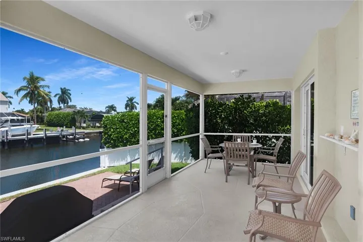 Screened-in patio with direct water access, concrete flooring, and a white framed enclosure