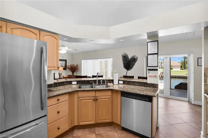 Kitchen featuring a double basin sink, granite-style countertops, stainless steel appliances, wood cabinetry, and recessed lighting