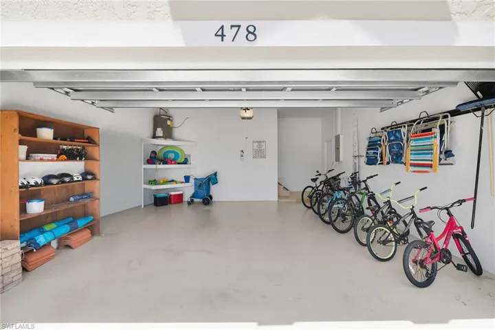 Expansive garage with durable concrete flooring, built-in wooden shelving, and wall-mounted storage racks