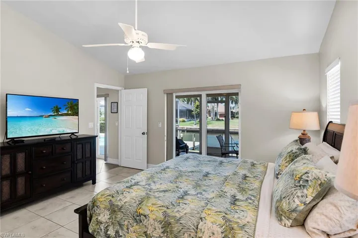 Vaulted ceilings, a white ceiling fan, tile flooring, and sliding glass doors leading to a screened outdoor area