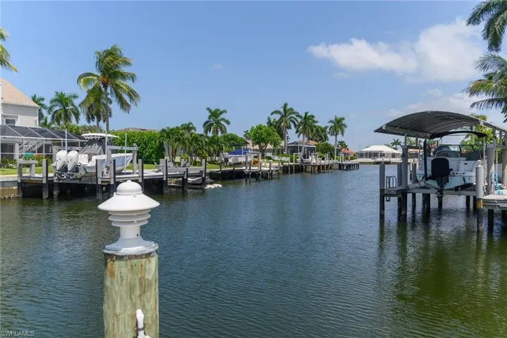 Waterfront property with multiple boat docks, boat lifts, and mature palm trees