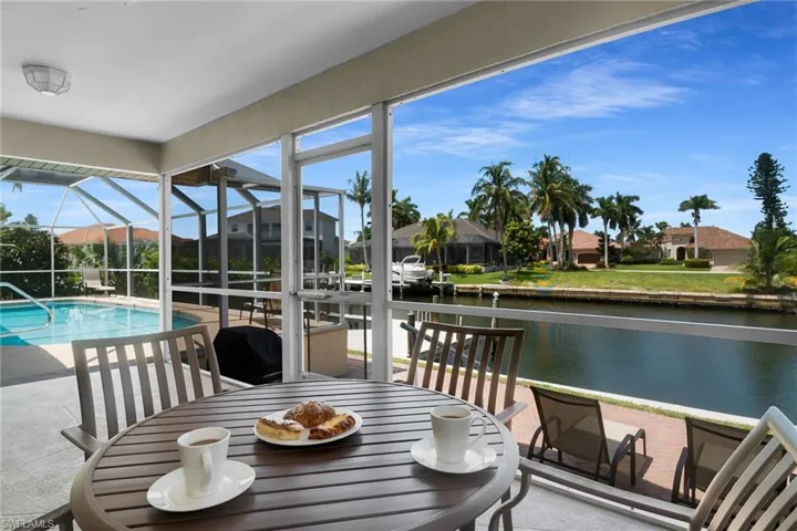 Screened-in outdoor living space featuring a swimming pool, covered patio, and direct canal access