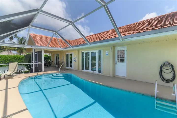 Screened pool enclosure with a pool and integrated steps, featuring an exterior entry door and multiple sets of glass doors accessing the interior