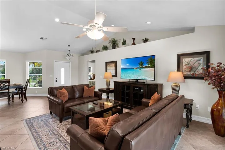 Vaulted ceiling with a ceiling fan, recessed lighting, tile flooring, and multiple windows