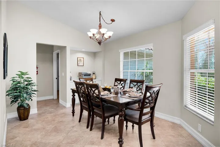 Vaulted ceiling, tiled flooring, recessed built-in shelving, and multiple windows