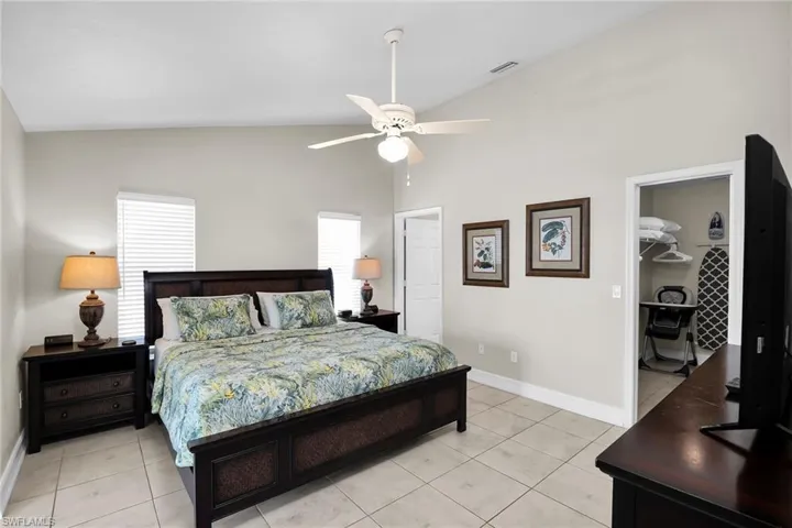 Vaulted ceiling with a ceiling fan, tiled flooring, and multiple windows with blinds