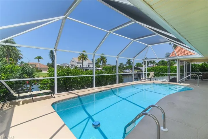 Screened enclosure with an in-ground swimming pool, concrete deck, and direct water access