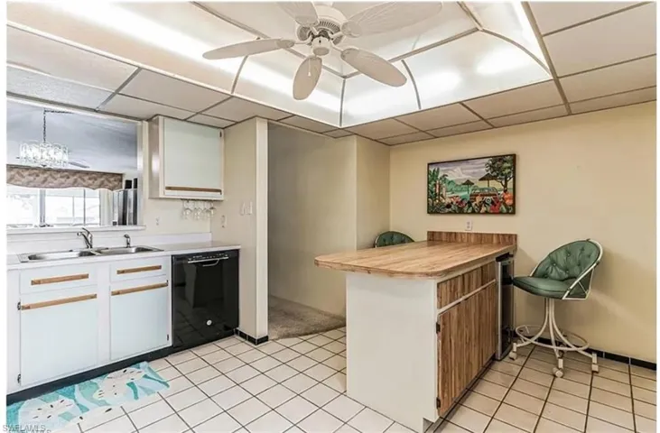 Kitchen with black dishwasher, white cabinets, sink, ceiling fan, and a paneled ceiling