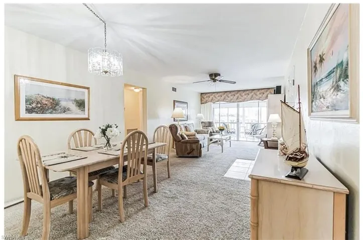 Dining space with light carpet and ceiling fan with notable chandelier