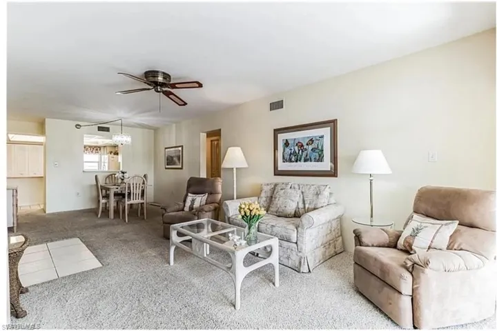 Carpeted living room featuring ceiling fan with notable chandelier