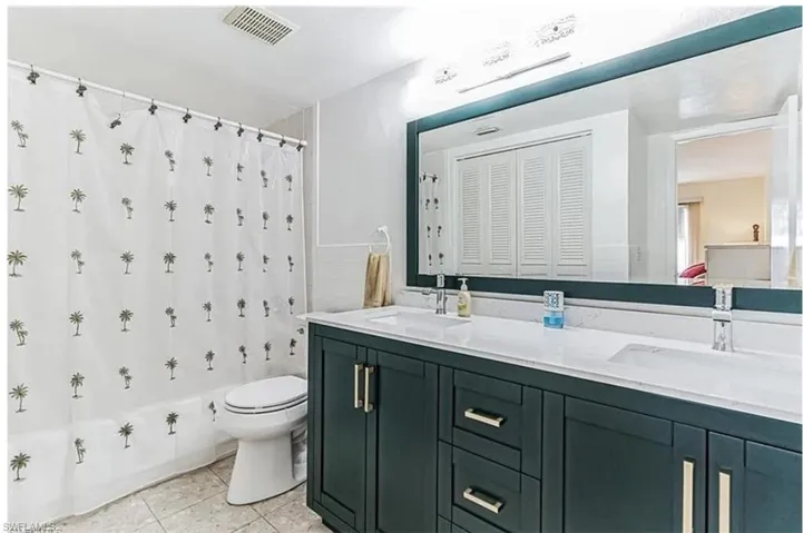 Full bathroom with toilet, shower / tub combo, tile patterned floors, and vanity