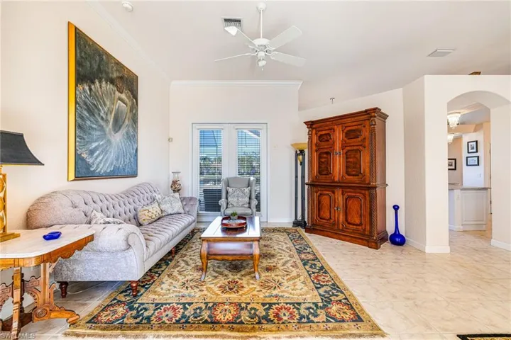 Living area featuring ceiling fan, crown molding, and arched walkways