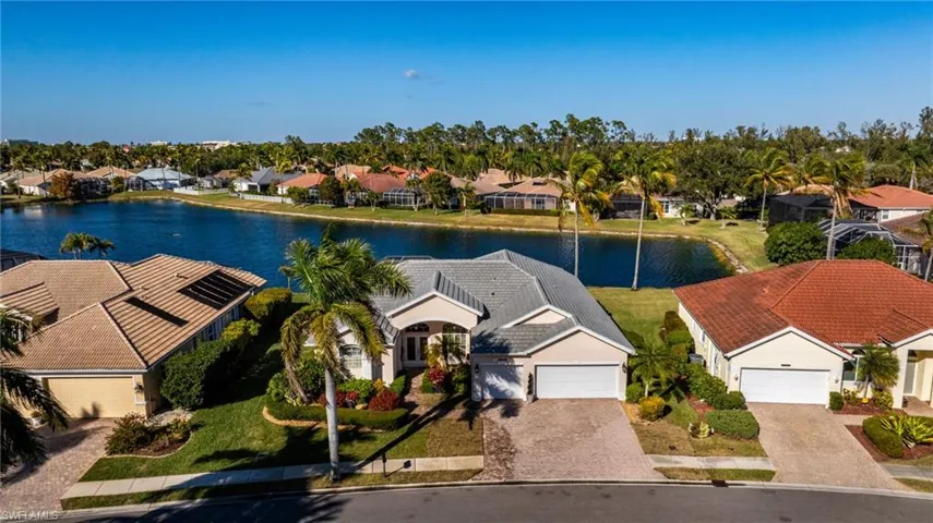 Aerial view of residential area featuring a nearby body of water and a tree filled landscape